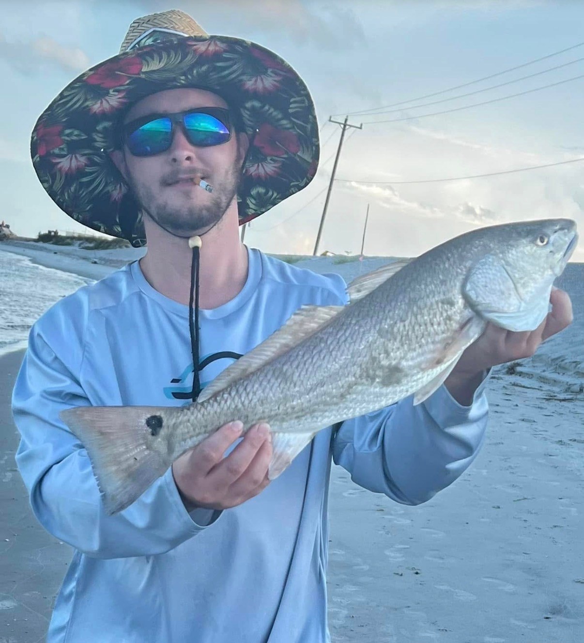 Angler holding a red drum on the beach