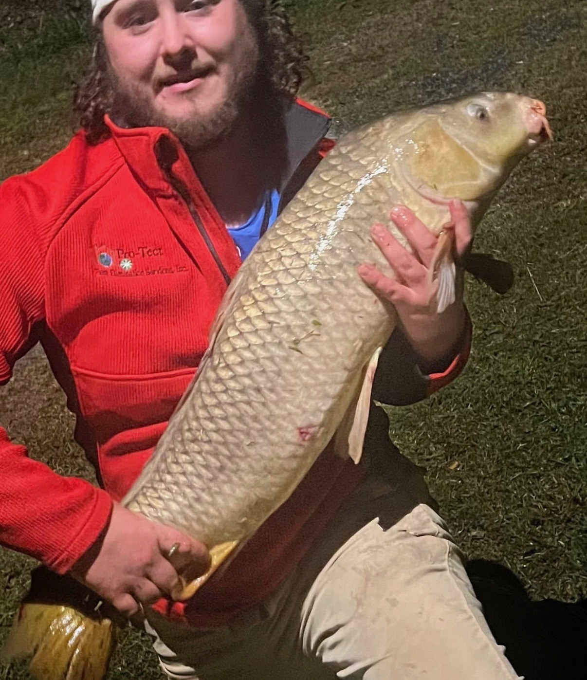 Angler holding a large carp at night