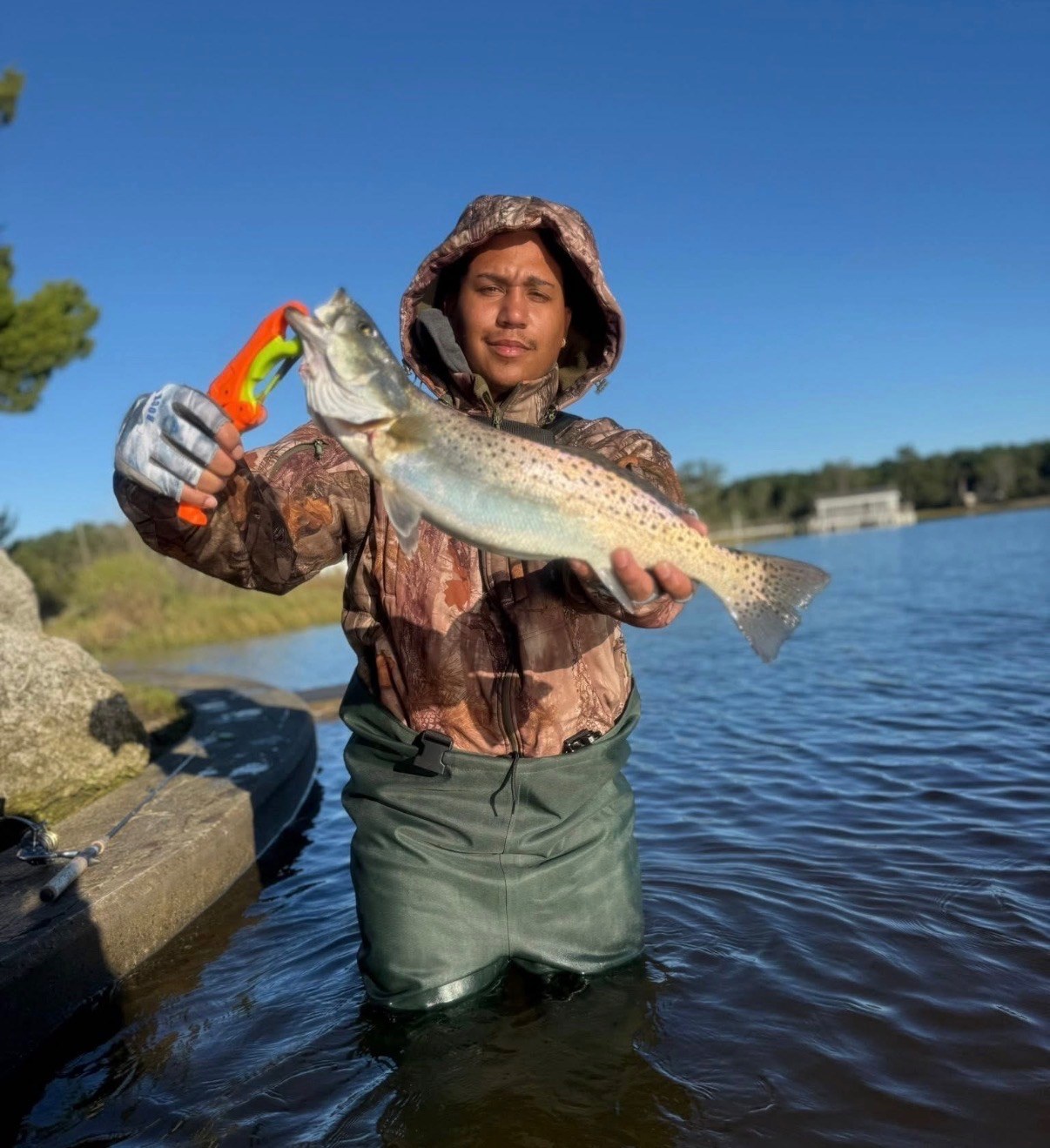 Angler in waders holding a speckled trout