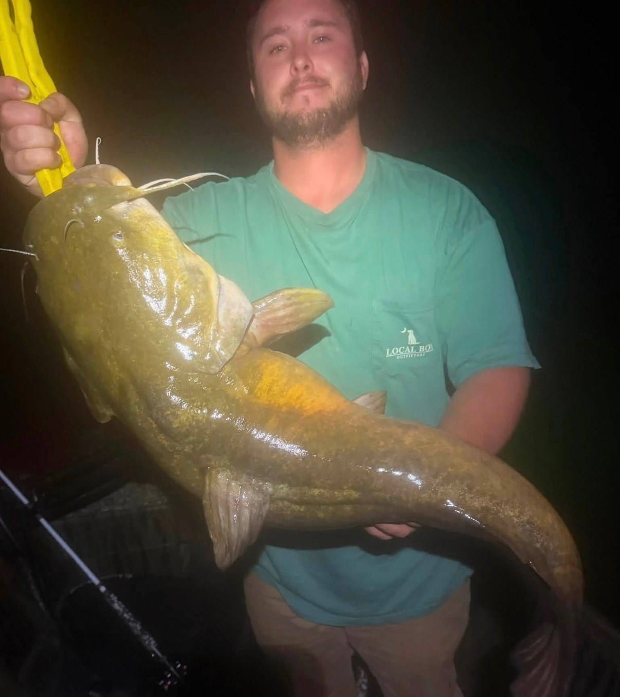 Angler holding a large catfish at night