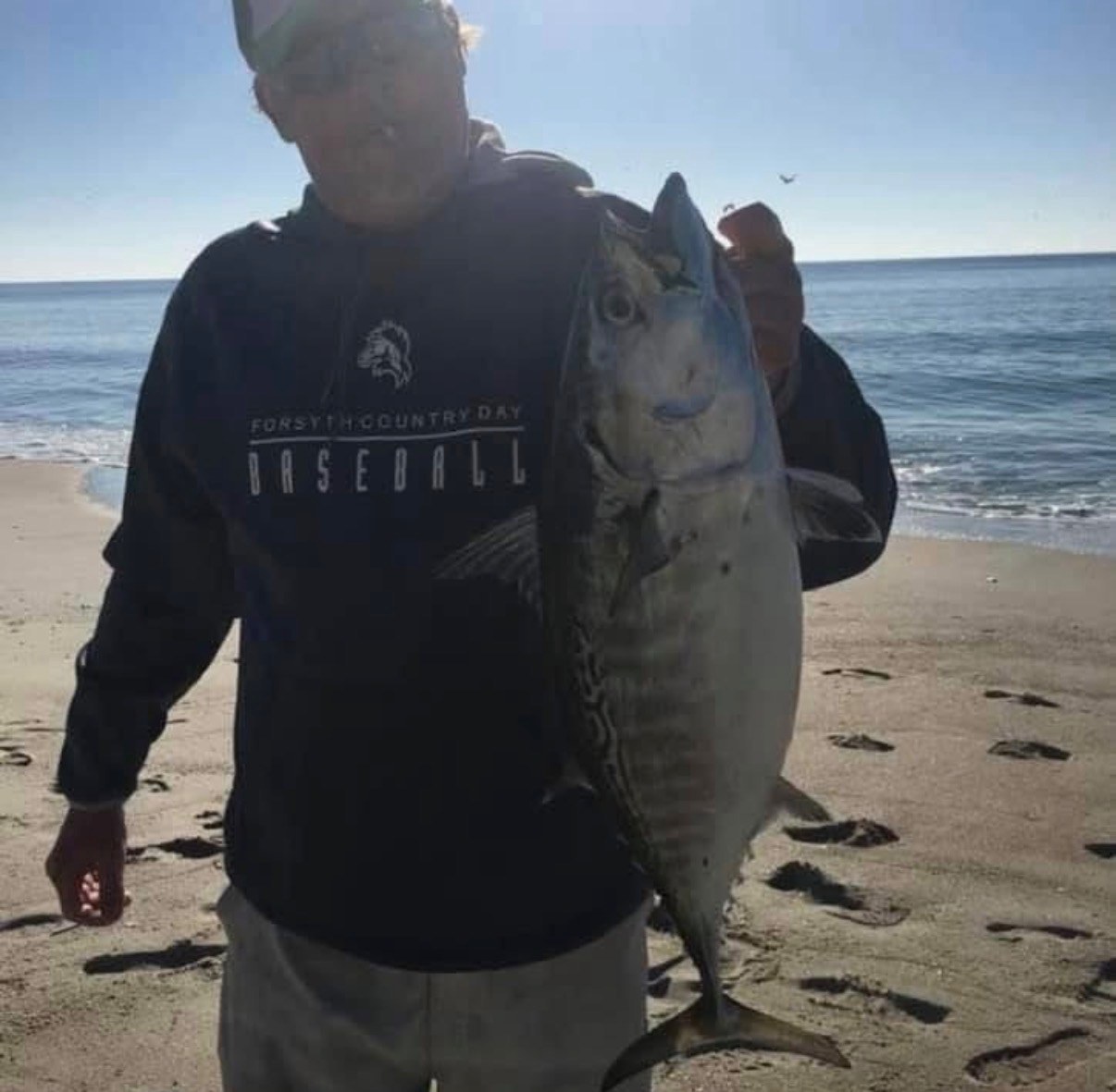 Angler on the beach holding a saltwater gamefish