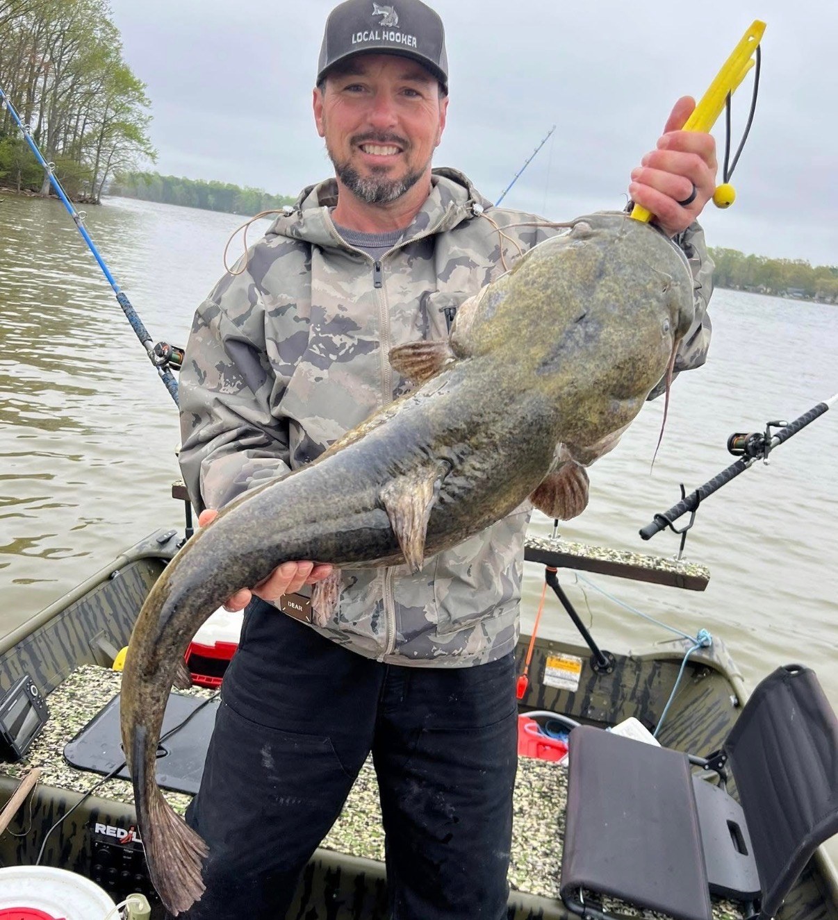 Angler in a boat holding a large flathead catfish
