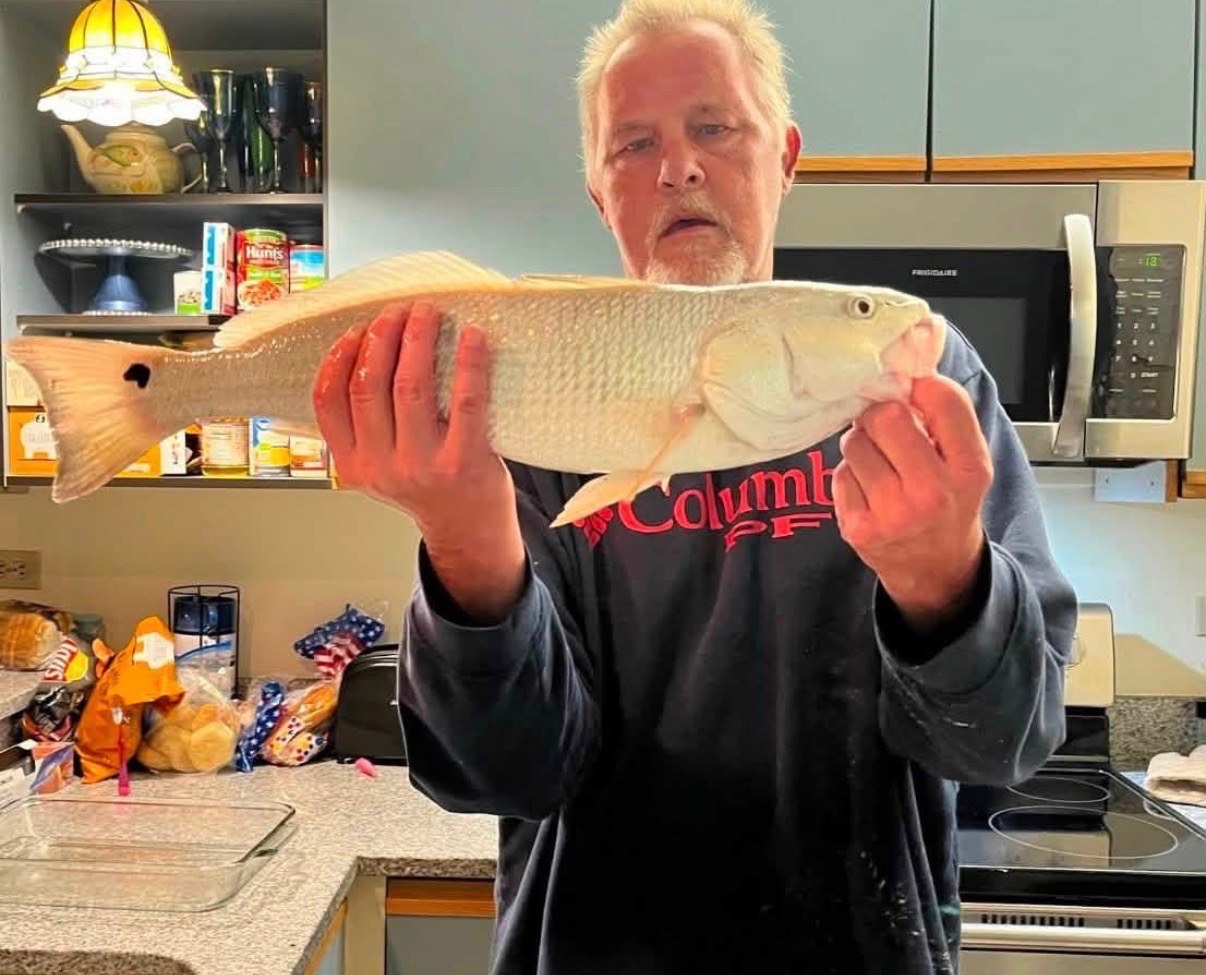Angler holding a red drum in a kitchen